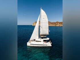 A stunning aerial view of a Bali catamaran sailing through crystal-clear waters, showcasing its elegant design against a picturesque coastal backdrop.