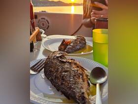 Delicious grilled fish served on a boat during sunset, perfect for a memorable dining experience on the water.