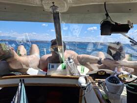 A group of friends relaxes on the deck of a boat, enjoying drinks and the beautiful water views — a perfect day for leisure on the sea.