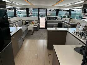 A spacious and elegantly designed interior of a yacht, featuring a comfortable dining area and modern kitchen amenities, perfect for entertaining guests on the water.