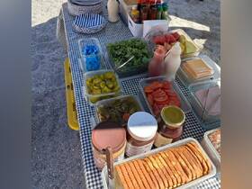 A vibrant spread of snacks and condiments laid out on a table, perfect for a day on the water or a beach picnic.