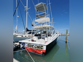 A striking view of the 'Side Chic' boat docked at Port Aransas, Texas, showcasing its sleek design and vibrant colors against a clear blue sky.