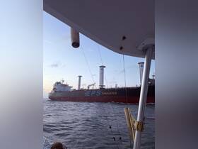 A close-up view of a large tanker ship navigating through the ocean, captured from another boat, showcasing the dynamic maritime environment.