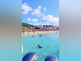 A lively beach scene with people enjoying the turquoise waters, perfect for swimming and relaxation under the sun.