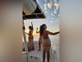 A vibrant group of friends enjoys a sunset celebration on a boat, capturing the perfect moment of joy and camaraderie against a stunning backdrop.