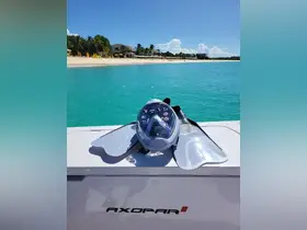 A snorkel mask and fins are displayed on the deck of an Axopar boat, set against a stunning turquoise backdrop — perfect for underwater adventures in tropical waters.