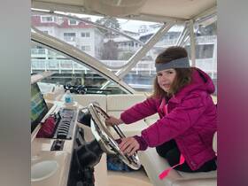 A young girl playfully sits at the helm of a boat, showcasing the cozy interior space. Perfect for family outings and introducing kids to boating.