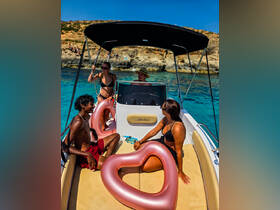 A lively group enjoys a sunny day on a boat, complete with heart-shaped floaties, perfect for a fun day on the water.