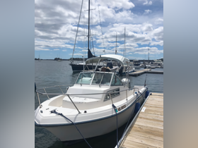 A speedboat docked at the marina, showcasing its sleek design against a backdrop of other vessels and a beautiful sky.