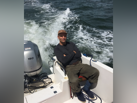 A man relaxes on a boat, enjoying the ocean breeze as the vessel speeds through the water — a perfect moment for boating enthusiasts.