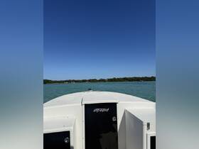 A clear view of the front of an Intrepid boat cruising through calm turquoise waters, showcasing the vessel's sleek design against a bright blue sky.