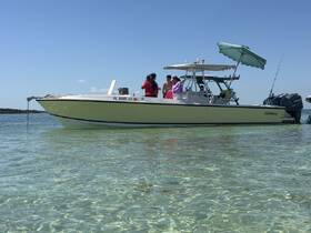A lively group enjoys a sunny day on the water, gathered around a pontoon boat with a beach umbrella, perfect for summer fun and relaxation.