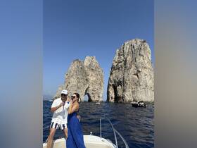 A couple enjoys a toast on a boat near iconic rock formations, capturing a perfect moment of celebration amidst stunning scenery.