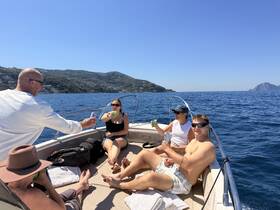 A lively group enjoys drinks on a boat under the sun, capturing the essence of a perfect day on the water with friends.