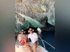 A couple enjoys a scenic moment on their boat inside a stunning cave, showcasing the beauty of their adventure on the water.