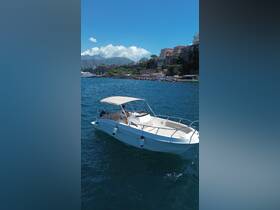 A sleek speedboat navigates the clear waters, showcasing its elegant design against a stunning coastal backdrop.