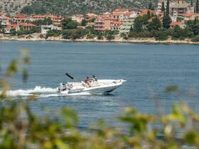 A speedboat glides through calm waters, showcasing a picturesque coastal backdrop — perfect for exploring scenic destinations.