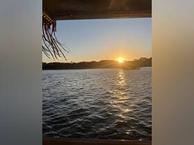 A serene sunset view over the water, framed by the edge of a boat, creating a picturesque scene perfect for evening cruises.