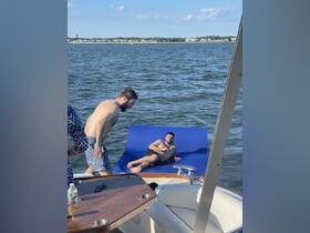 A lively scene on the water with friends enjoying a floating mat, perfect for summer parties and relaxation on a boat.