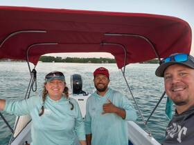 A cheerful group of boaters poses for a selfie on the water, capturing the joy of their boating experience as the sun sets in the background.