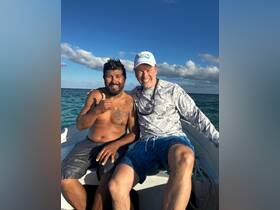 Two friends share a joyful moment on a boat, showcasing camaraderie and adventure on the water — perfect for memorable outings and fishing trips.