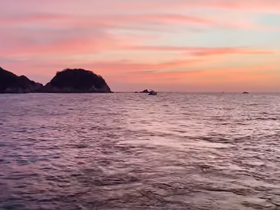 A stunning sunset over the coastline, with tranquil waters reflecting the vibrant colors of the sky — an ideal backdrop for evening boat cruises.
