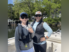 A smiling woman and a boy wearing life jackets pose together on a boat, ready for a fun day on the water. Perfect for family outings and boating adventures.