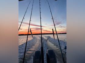 A stunning sunset view from a fishing boat, showcasing fishing rods and the wake of the boat as it glides through tranquil waters — perfect for fishing enthusiasts and sunset lovers.