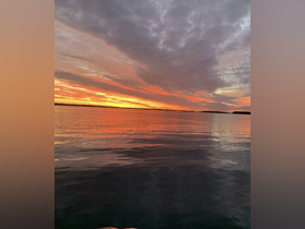 A stunning sunset reflects on calm waters, creating a picturesque scene perfect for evening boat outings.