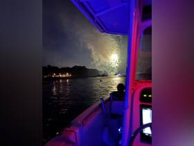 A stunning view of fireworks lighting up the night sky from a boat, creating a festive atmosphere perfect for celebrations on the water.