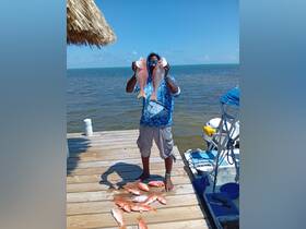 A proud angler displays his impressive catch of fish on the dock, showcasing a successful day of fishing in beautiful waters.