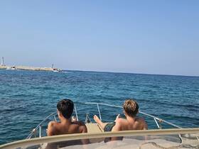 Two young men relax on the bow of a boat, enjoying the serene ocean view — a perfect summer getaway on the water.