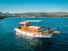 A beautiful wooden yacht anchored in clear blue waters, showcasing its elegant design against a scenic backdrop of mountains.