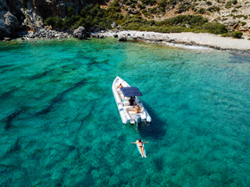 A relaxing scene featuring a group enjoying a sunny day on a boat, with one person floating in the crystal-clear waters — perfect for summer adventures and beach outings.