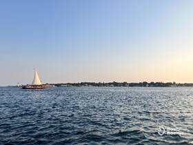 A picturesque view of a sailboat gliding through calm waters, with a charming shoreline in the background, perfect for showcasing serene sailing experiences.