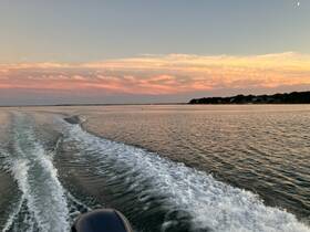 A serene sunset view over calm waters, showcasing the beautiful coastline and vibrant sky — perfect for capturing the essence of a peaceful boating experience.