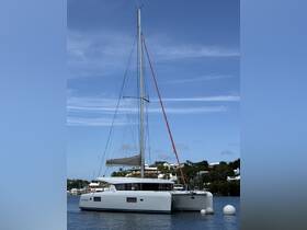 A sleek catamaran docked in calm waters, showcasing its modern design against a backdrop of lush greenery and blue skies — perfect for luxury sailing experiences.