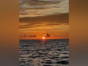 A breathtaking sunset over the ocean, casting vibrant colors across the sky and water — a perfect moment for relaxation and reflection on a boat trip.