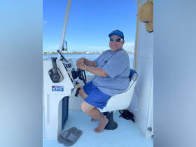 A smiling man sits at the helm of a boat, ready to navigate the waters. The interior showcases the boat's console and seating, perfect for a day of adventure on the water.