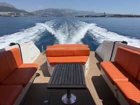 Interior view of a stylish boat lounge area featuring comfortable orange seating and a table, perfect for relaxing while cruising on the water.