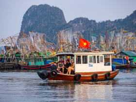 A group enjoys a scenic boat ride in Vietnam, surrounded by vibrant fishing boats and stunning landscapes — a perfect snapshot of local maritime culture.