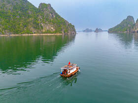 A scenic aerial view of a boat navigating through tranquil waters, surrounded by lush green hills and rocky formations, perfect for exploring beautiful landscapes.
