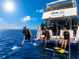 A group of divers prepares to enter the vibrant waters of the Red Sea, showcasing an exciting scuba diving experience with a diving center.