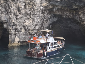 A group of guests enjoys a scenic boat ride exploring a stunning cave, showcasing the beauty of nature and adventure on the water.