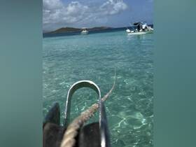 An unclear image featuring a close-up of a pulley and rope, with boats visible in the background. The focus is ambiguous, making it difficult to determine the primary subject.