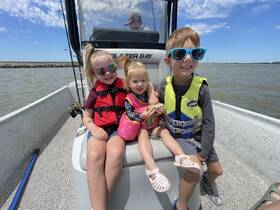 Three children enjoy a fun day on the water, wearing life jackets and smiling aboard a boat — a perfect family adventure.
