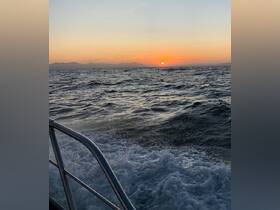 A serene sunset view over the water, captured from the side of a boat, showcasing the tranquil beauty of the sea.