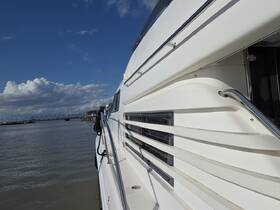 A close-up view of the sleek side of a yacht, showcasing its elegant design against a backdrop of blue skies and calm waters.