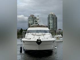 A stunning yacht is docked with a clear view of its front profile, showcasing its elegant design against a backdrop of modern buildings.