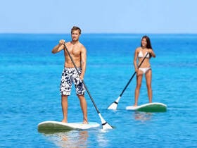 A couple enjoys paddleboarding in crystal-clear waters, showcasing the perfect blend of adventure and relaxation on the water.